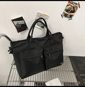 Close-up of black travel tote with two front zipper pockets and durable nylon fabric