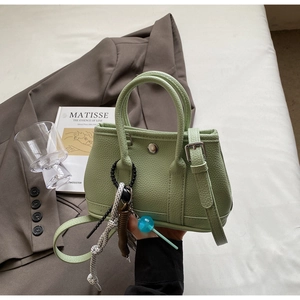 Detail der minzgrünen Beuteltasche mit Lederstruktur und dekorativen Accessoires