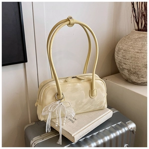 Close-up of pale yellow Boston bag with lace pearl bow charm on vintage books