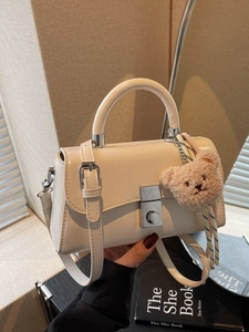 Chic beige crossbody bucket bag with silver clasp and plush bear charm decoration