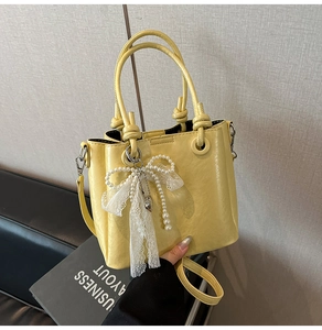 Détail du sac seau jaune clair avec breloques perles et nœud dentelle sur cuir PU