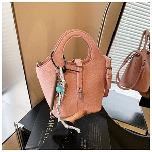 Detail of pink bucket bag with lychee texture leather and decorative pendant charms