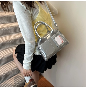 Detail of silver metallic PU pillow bag featuring a transparent card slot and top handle