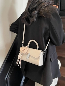 Chic cream leather bucket bag with cute plush bear charm and crossbody strap