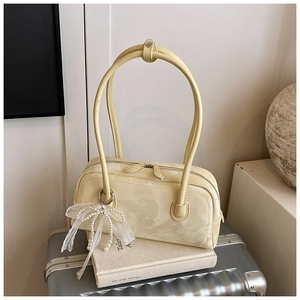 Detail of cream shoulder bag with double long handles and elegant pearl lace bow pendant