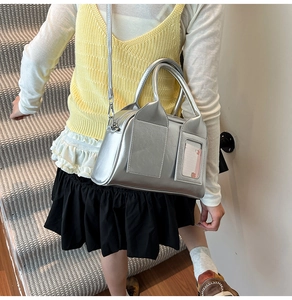 Borsa Boston argento opaco con tracolla e tasca ID indossata da una modella sulle scale