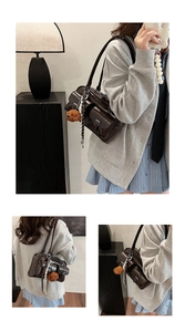 Close-up of retro brown PU leather shoulder bag with metallic buckles and plush bear charm