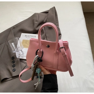 Detailansicht der rosa Lederstruktur und Metallschnalle an der Eimer-Handtasche