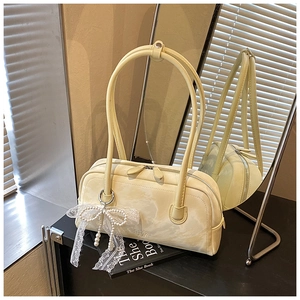 Detail of cream shoulder bag with marble texture and pearl bow charm on books