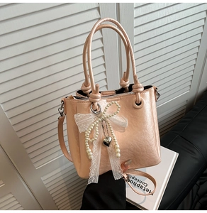 Détail du sac seau en similicuir rose clair avec nœud perlé et pendentif en cœur