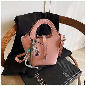 Detailed view of pink pebble leather bucket bag with cute bear and colorful charms