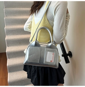 Close-up of silver metallic shoulder bag featuring a transparent window pocket and card