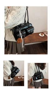 Detail of black PU leather Boston bag with silver buckles and plush bear charm accessory
