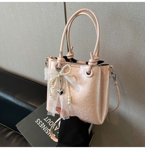 Détail du sac seau rose avec nœud en dentelle, breloque en perles et poignée nouée