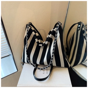 Detail of black and white striped knit tote with leather strap and chain accent