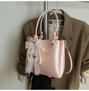 Vue détaillée du sac seau rose nacré avec nœud en dentelle et pendentif en cœur