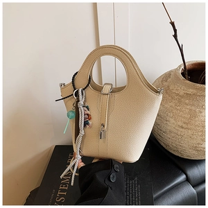 Detail of beige leather bucket bag with silver lock and colorful decorative pendants