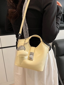 Cream bucket bag for women with heart charm and shoulder strap in casual setting