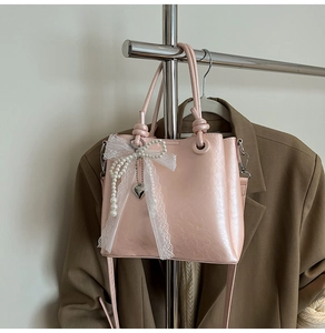 Vue détaillée du sac rose avec nœud en dentelle, chaîne de perles et pendentif cœur