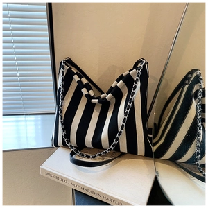 Detail of striped canvas tote bag with chain strap against aesthetic sunlight shadows