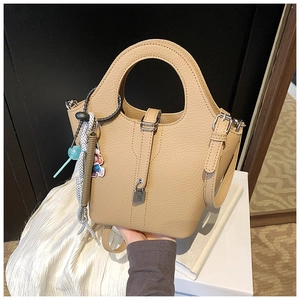 Detail of light tan bucket bag with pebble leather texture and silver lock closure