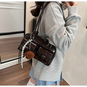 Detail of dark brown faux leather pillow bag with multiple pockets and cute bear charm