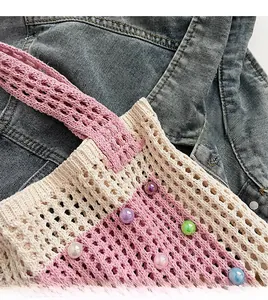 Detail of hand-woven tote bag with colorful beads and soft pink knit on denim background