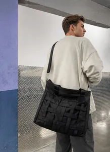 Detail of black woven nylon messenger bag with thick textured straps and adjustable band