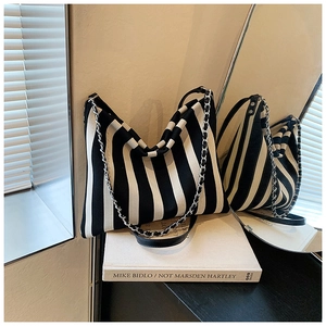 Detail of a large striped canvas hobo bag with a decorative silver metal chain strap
