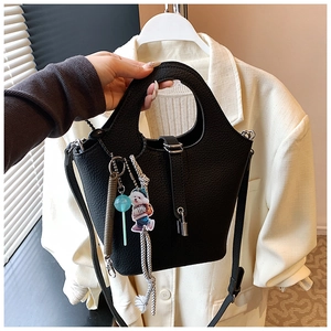 Detail of black pebbled leather bucket bag with silver lock and colorful charms