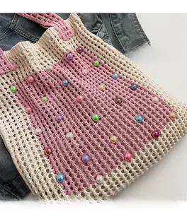 Close-up of handmade crochet bag with colorful pearl beads on denim background