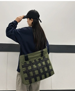 Detail of army green nylon crossbody tote bag with black woven webbing and zipper
