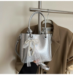 Détail du sac seau métallisé argenté avec nœud en perles et finitions en dentelle