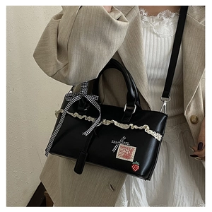 Detailed close-up of lace tote bag with checkered bow and strawberry charm accent