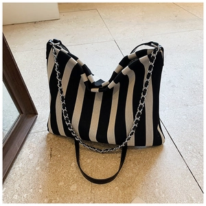 Detail of striped canvas tote bag showing black and white texture with chain strap