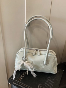 Mint green textured baguette bag with lace bow and pearl pendant on books