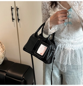 Detail of black patent leather crossbody bag with a transparent front card slot and strap