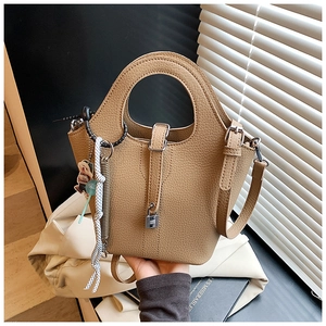 Close-up of pebble leather bucket bag featuring a circular handle and bear charm