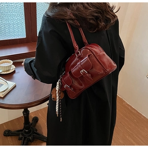 Close-up of a retro deep red glossy leather shoulder bag with bear charm detail