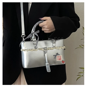 Detail of silver lace handbag with checkered bow, strawberry charm and bunny patch