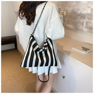 Detailed shot of black and white striped canvas tote with woven metal chain strap