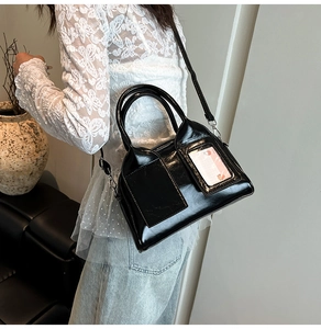 Detail of black patent leather pillow bag with glossy finish and clear card slot detail