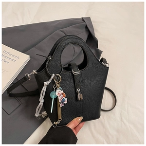 Detail of black lychee grain bucket bag with metal lock and cute cartoon charms