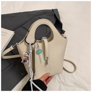 Detail of off-white lychee pattern bucket bag with metal lock and cute hanging charms