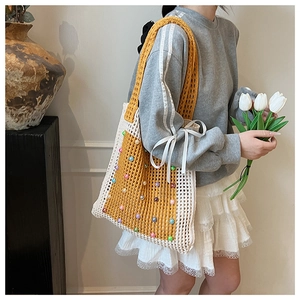 Detailed knit texture of the yellow and white tote bag with colorful pearl embellishments