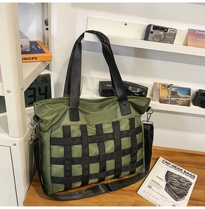 Detail view of large olive green nylon tote bag featuring black web mesh and metal hardware