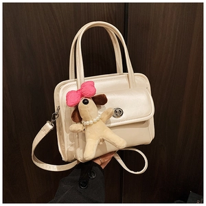 Detail of cream leather handbag with silver twist lock and cute plush puppy charm