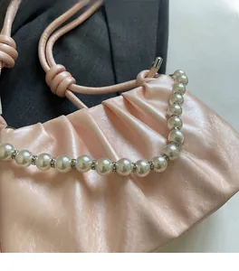 Detail of pink pleated cloud bag featuring large white pearls and crystal embellishments
