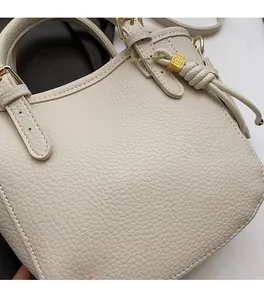 Detail showing high-quality lychee textured cream leather with tassel and gold hardware