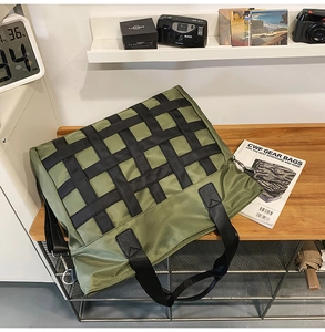 Detail of olive green nylon tote bag with black woven patterns in a modern studio setting